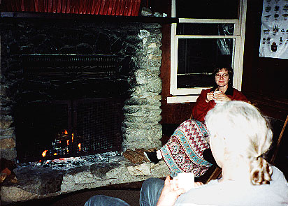 Nan enjoys drink by fireplace -- by Valerie